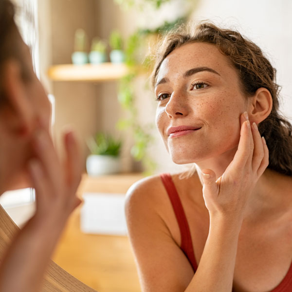 woman examining face in mirror