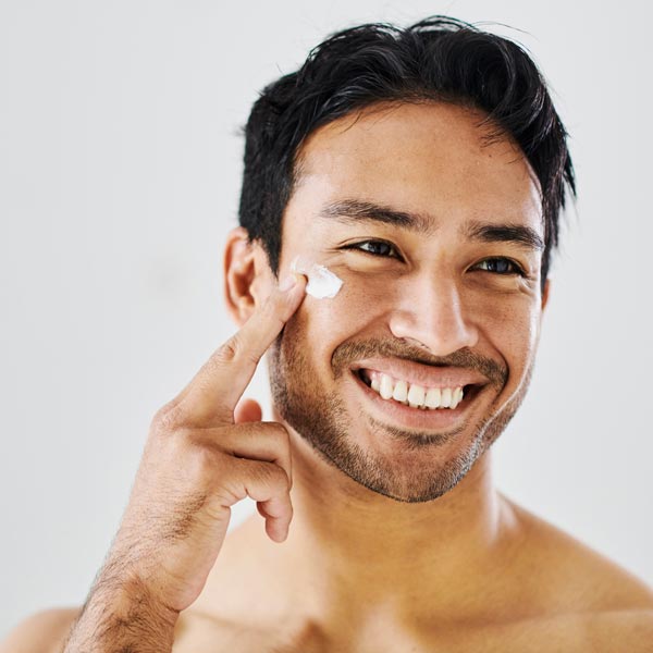 man applying cream to face smiling