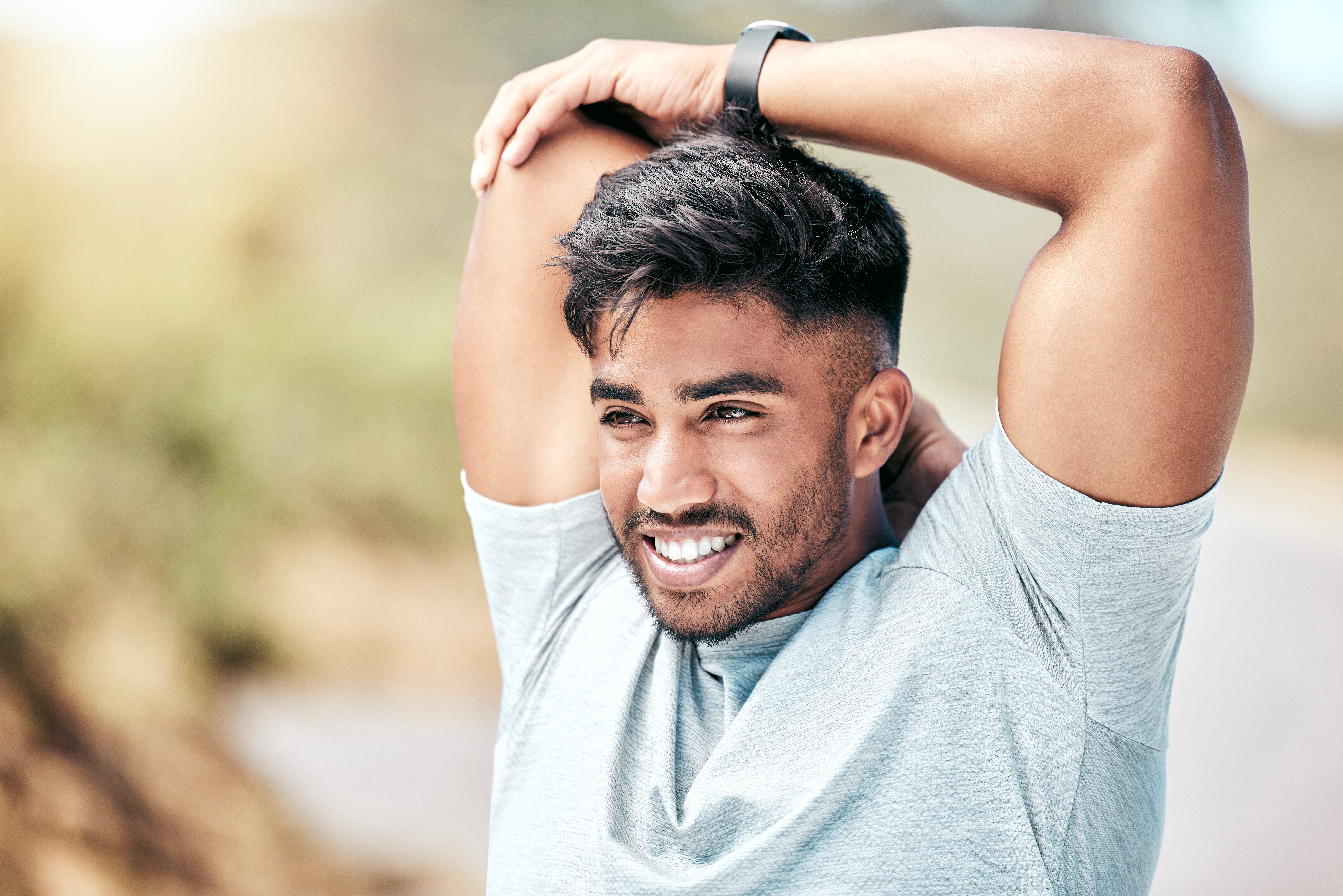 Handsome man with full head of hair stretching outdoors